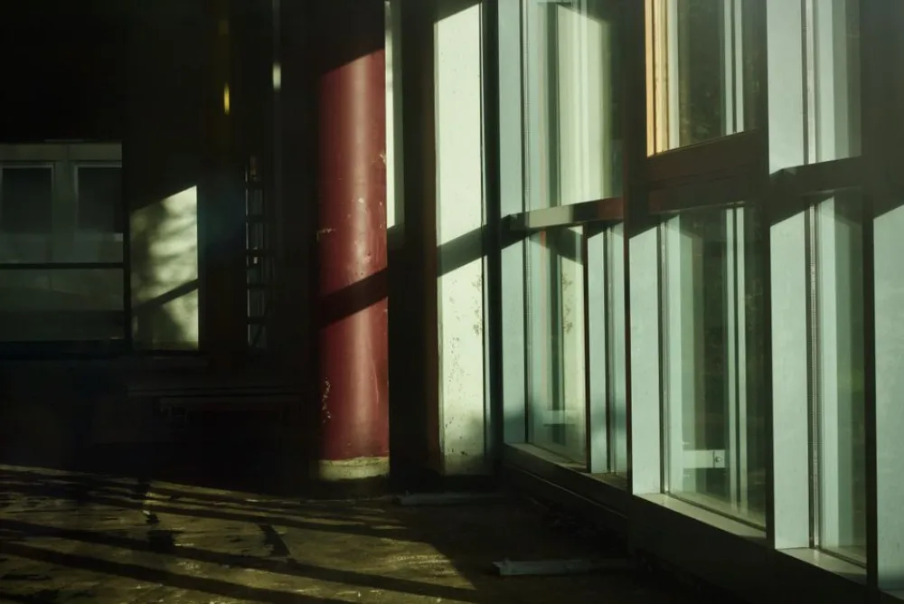 Sunlight streaming through industrial windows casting dramatic shadows indoors.