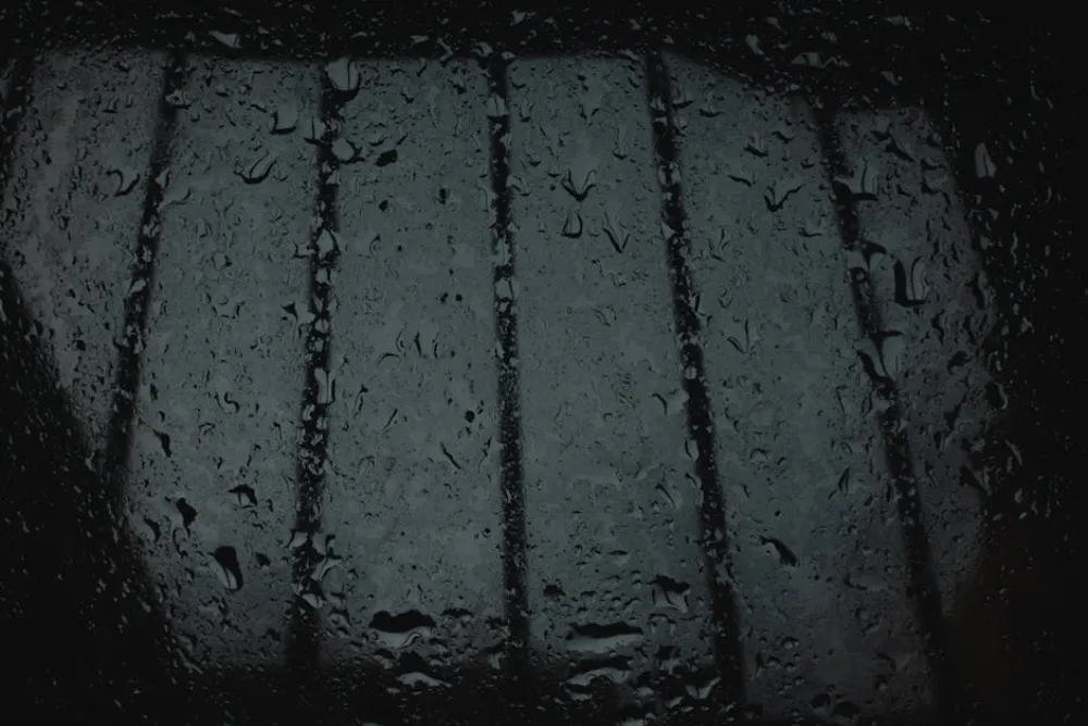 Close-up of rain droplets on a windowpane, creating a moody atmosphere.