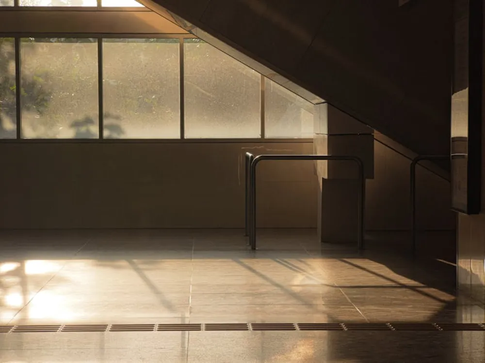 A quiet, sunlit interior space with geometric shadows and minimalist design elements.