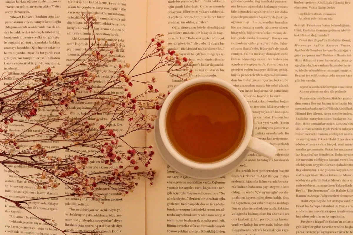 Кружка кофе на открытой книге с сухоцветами, вид сверху.